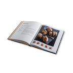 Aufgeschlagenes Backbuch mit Brötchen.