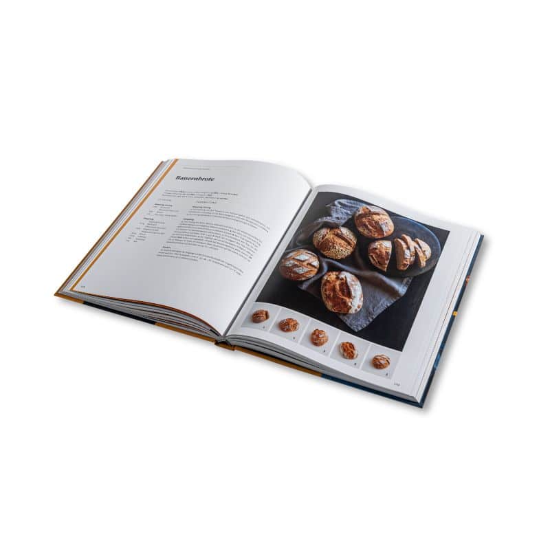 Aufgeschlagenes Backbuch mit Brötchen.