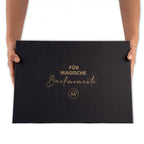 Hände halten schwarze Geschenkbox