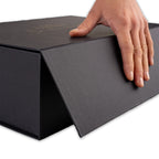 Hand öffnet schwarze Geschenkbox