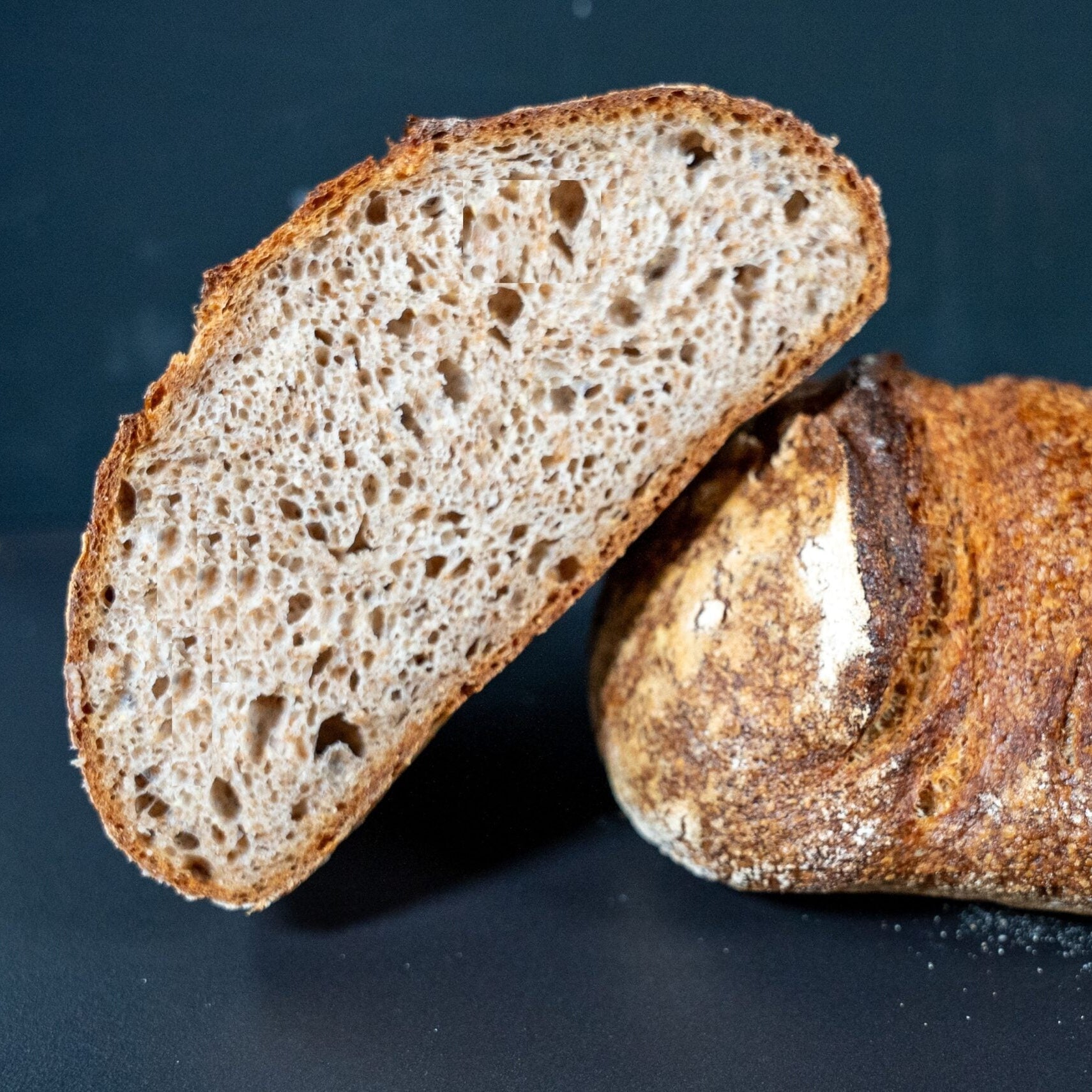 Aufgeschnittenes Sauerteigbrot auf schwarzem Hintergrund