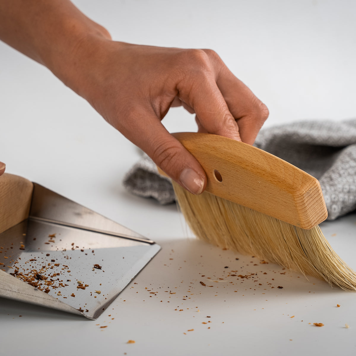 Hand fegt Krümel mit Handfeger