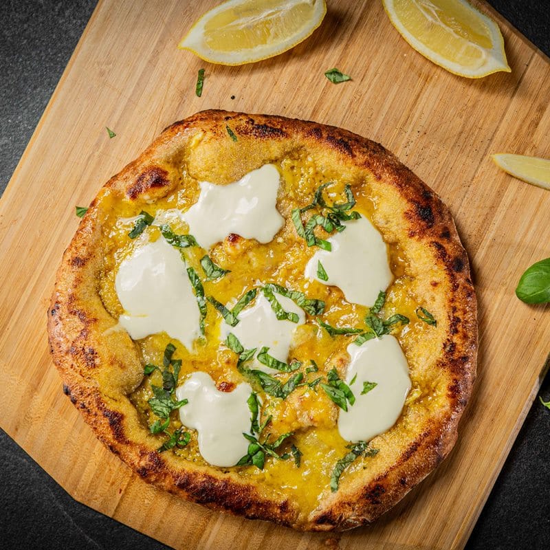 Pizza mit Zitronenspalten auf Holzbrett